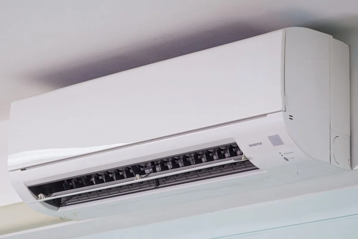Condizionatore split bianco montato a parete, appena sotto il soffitto
